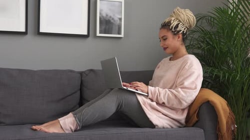 Woman Using Laptop on Sofa Indoors