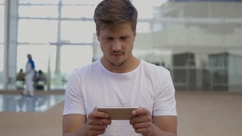 Front View of Smiling Young Man Using Smartphone