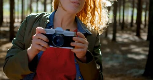 Woman Taking Pictures in Forest with Vintage Camera