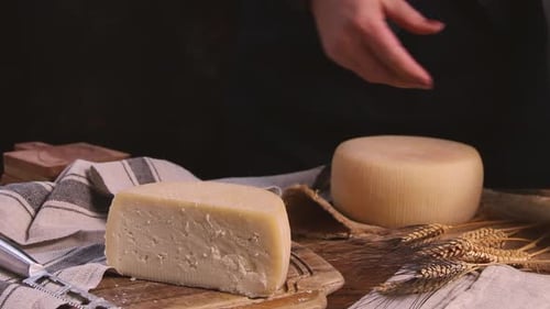 Women hands put pieces of fresh homemade cheese on a wooden board close up