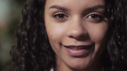 Young Woman Smiles with Flowers in Close Up