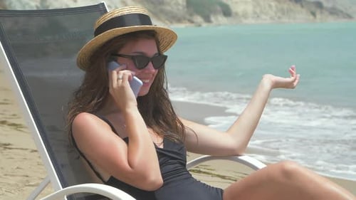 Woman Chatting on Mobile Phone at Beach