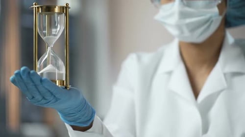 Medical Worker Holding Sand Hourglass on Palm, Terminal Disease, Life Expiring