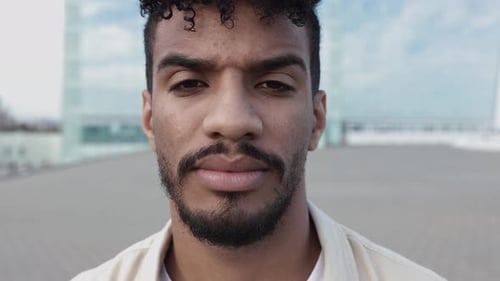 Serious Young Hispanic Latin Man Looking at Camera Standing in City Street