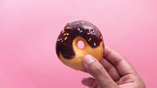 Hand Holding Chocolate Donut with Sprinkles