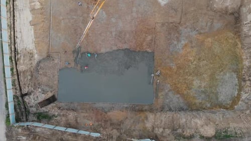 Vista aérea de trabajadores de la construcción vertiendo concreto en el sitio de construcción.