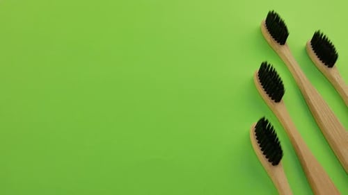 Bamboo Toothbrushes on Green Background with Copy Space