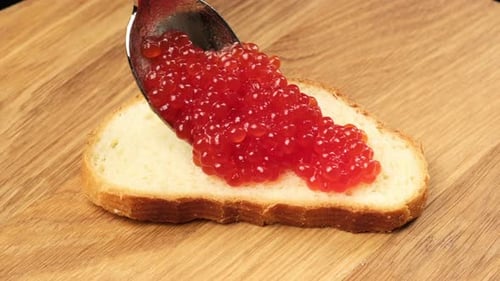 Red Caviar Being Spooned Onto Bread
