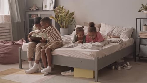 Children Using Tablet and Cell Phones on Bed