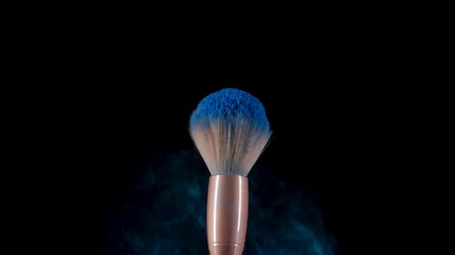 Fluffy Makeup Brush Flinches and Creates an Explosion of Small Particles of Blue Powder Against