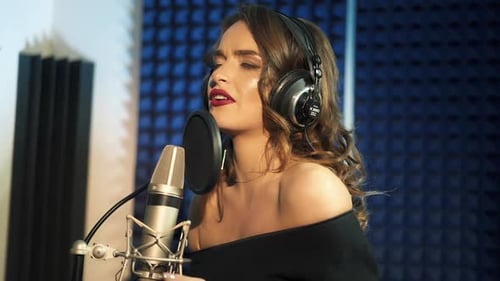 Close-up of girl in headphones singing a song. Professional recording studio