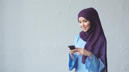 Muslim Girl in Hijab Uses Smartphone for Online Shopping.