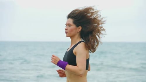 Woman Jogging Along the Beach on Overcast Day