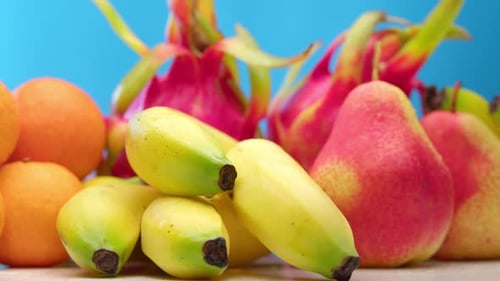 Frische, gesunde Früchte, Äpfel, Orangen, Bananen, Birnen, Drachenfrüchte auf blauem Grund, liegen auf weißem Grund