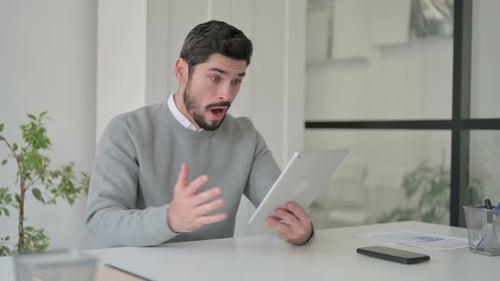 Young Man Reacting to Loss on Tablet While Sitting in Office