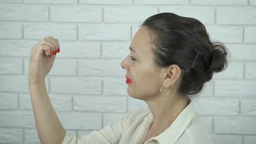 Woman Examines Fingernails with Magnifying Glass Indoors