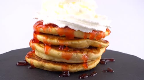 Stack of Pancakes Topped with Syrup and Whipped Cream