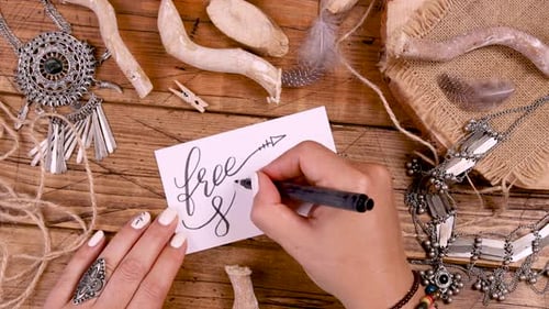 Hand Writing FREE SPIRIT card on a wooden table top view