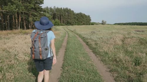 Woman Hiking Grassy Path in Rural Landscape
