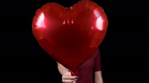 Young Adult Holds Heart Balloon on Black
