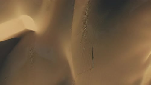 Aerial View of the Woman Walking By Sand Dunes in the Desert Nature