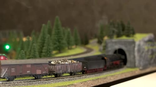 Trem de brinquedo com fumaça em movimento na ferrovia modelo.