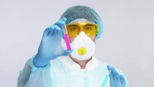 Científico médico muestra un tubo de ensayo rosa a la cámara con un traje de protección