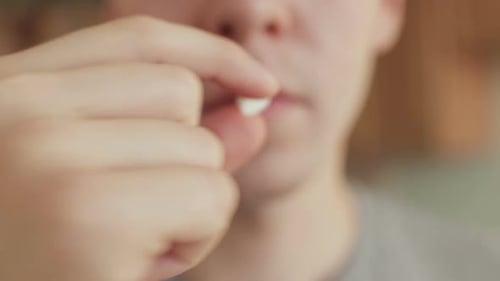 Young Adult Taking Pill with Glass of Water