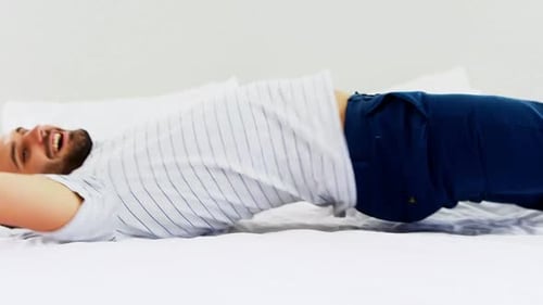 Man Relaxes Lying on Bed in Bright Room