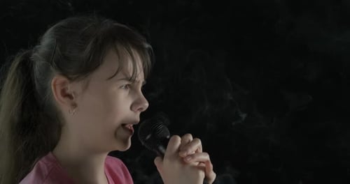 Child Singing into a Microphone on Dark Background