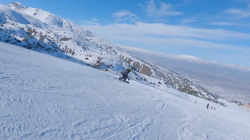Mann Snowboarder auf Snowboard läuft im Skigebiet die Piste hinunter