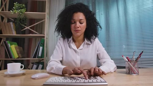 Portrait of African American Woman Typing on Computer Keyboard Looking Directly at Monitor
