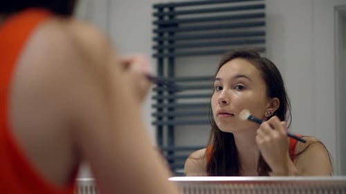 Young Woman Applying Make-up in Bathroom Mirror