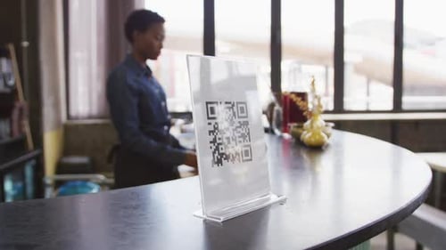 Mano de un cliente que usa un teléfono inteligente para leer el código QR en el bar de una cafetería