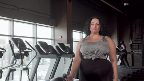 Beautiful Overweight Woman Exercising with Dumbbells at the Gym