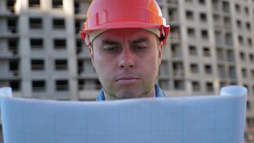 Confident Construction Engineer Reviews Blueprints On Site