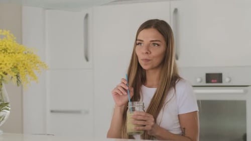 Young Woman Enjoys Refreshing Smoothie in Kitchen