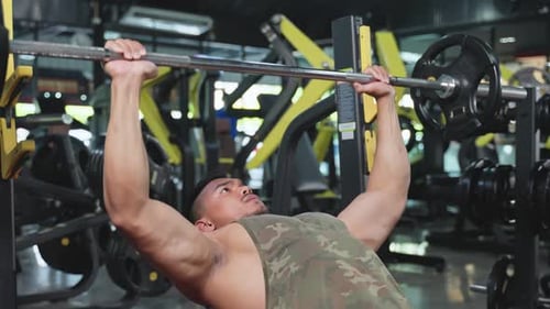 Asian active Fitness trainer sportman or athlete slowly lift up weight lifting or barbell in stadium