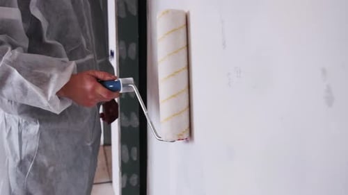 Man Painting Wall with Roller in House