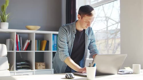 Ein junger männlicher Unternehmer arbeitet im Home Office am Computer.