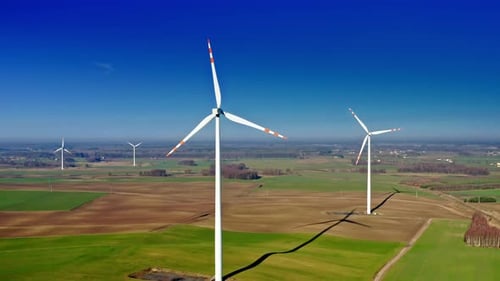Wind turbines with blue sky on farm field, aerial view