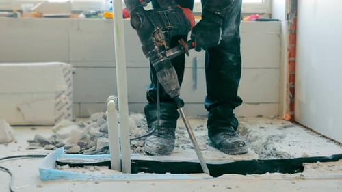 Worker Demolishes Concrete with Jackhammer Indoors
