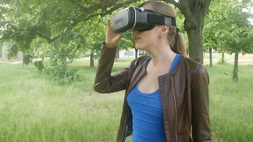 Young Cheerful Woman Uses A Modern Helmet Of Virtual Reality In The Park