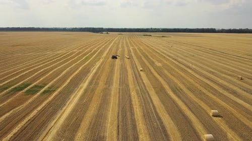 Luftaufnahme Traktorarbeit im Feld. Landwirtschaftliche Feld-Landschaft. Traktorladung von Heuballen