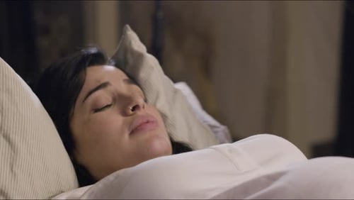 Frau liegt auf dem Bett und gebiert zu Hause