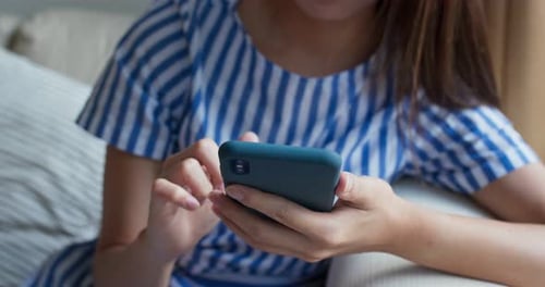 Woman Using Smartphone on Couch in Bright Home