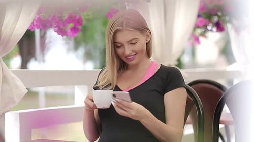 Smiling girl spending time in a street cafe using digital tablet
