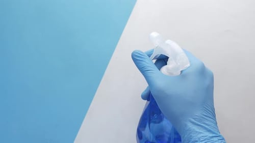 Spraying Bottle with Glove Against Blue and White Background