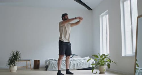 Man Warming Up, Stretching in Bright Bedroom