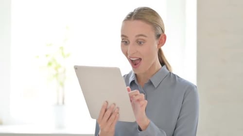 Woman Celebrates While Using Tablet Indoors